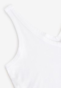 Débardeur blanc sans manches avec larges bretelles, tissu lisse et coutures visibles le long des bords.