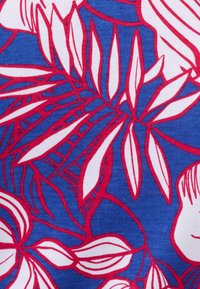 Tessuto con stampa floreale caratterizzato da uno sfondo blu con foglie tropicali bianche e rosa, che mostra una trama ondulata e un design audace e grafico.