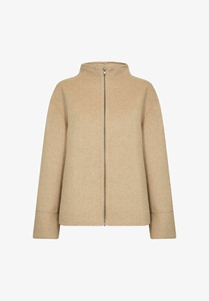 Beige gyapjú keverék kabát magas gallérral, elülső cipzárral és leesett vállvarrásokkal. Az anyag puha, texturált felületű.