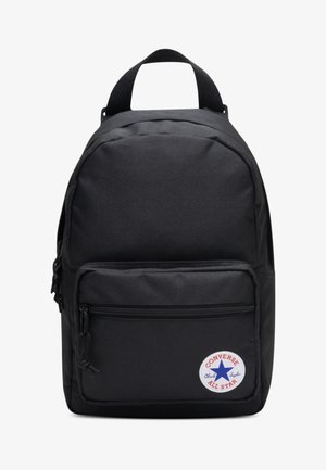 Zaino in tessuto nero con forma arrotondata, tasca frontale con cerniera e toppa con logo circolare che presenta una stella blu e dettagli testuali.