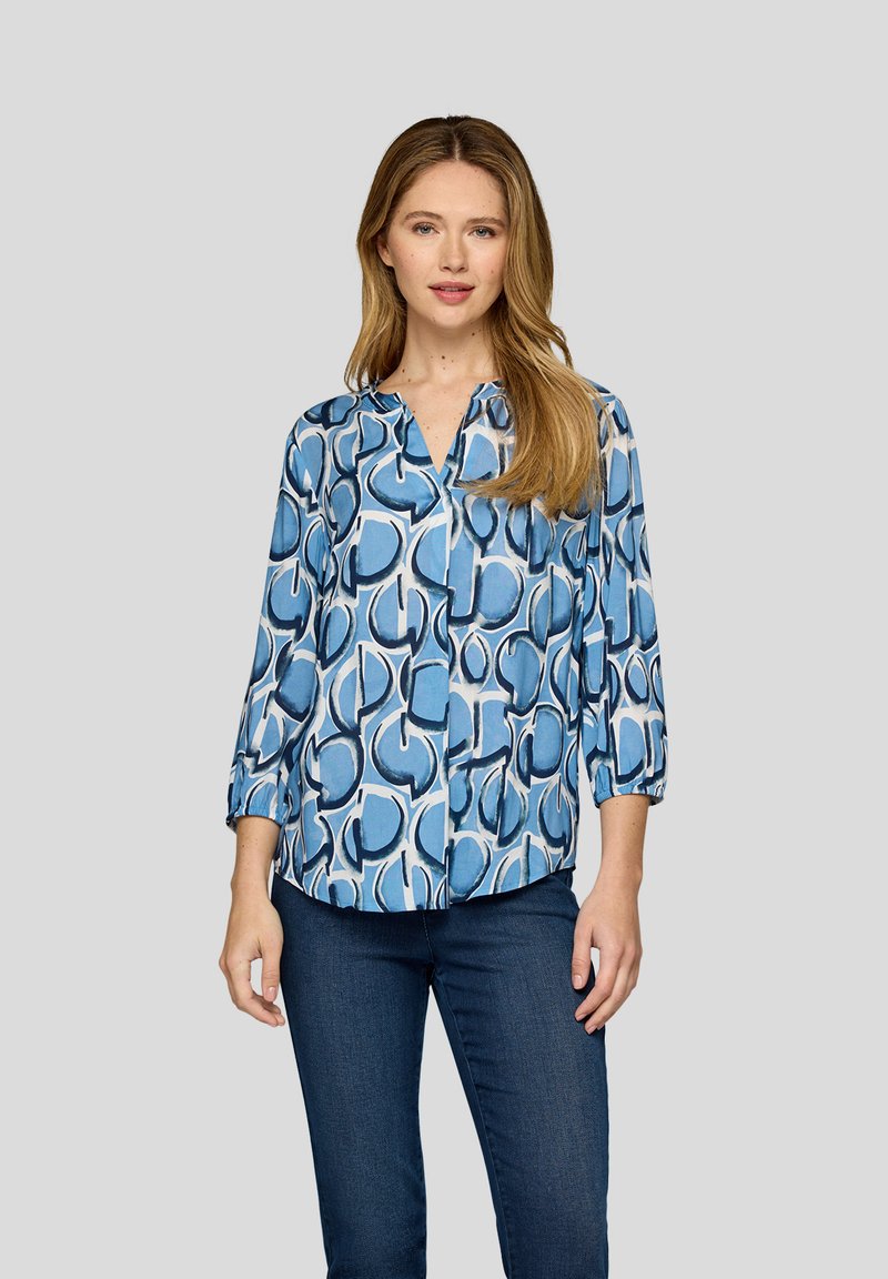 Helles blaues Blusenshirt mit einem abstrakten, kreisförmigen Muster in dunkleren Blautönen, langen Ärmeln mit umgeschlagenen Bündchen und einem V-Ausschnitt.