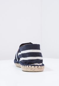 Marineblau-weiße gestreifte Espadrille mit einer Sohle aus Jute-Seil. Verfügt über einen abgerundeten Rücken und ein weiches Baumwoll-Obermaterial. Minimalistisches Design, keine sichtbaren Beschläge.