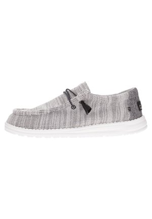Scarpa slip-on grigia in maglia con suola bianca, lacci elastici e un motivo testurizzato. Presenta un logo discreto sul lato e una punta arrotondata.