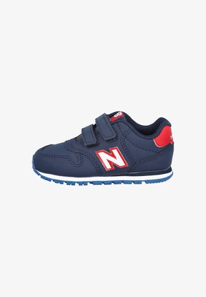 Zapatillas infantiles azul marino con detalles rojos, dos tiras de velcro, suela de goma y detalles blancos. Presenta el logo de New Balance en el lateral.