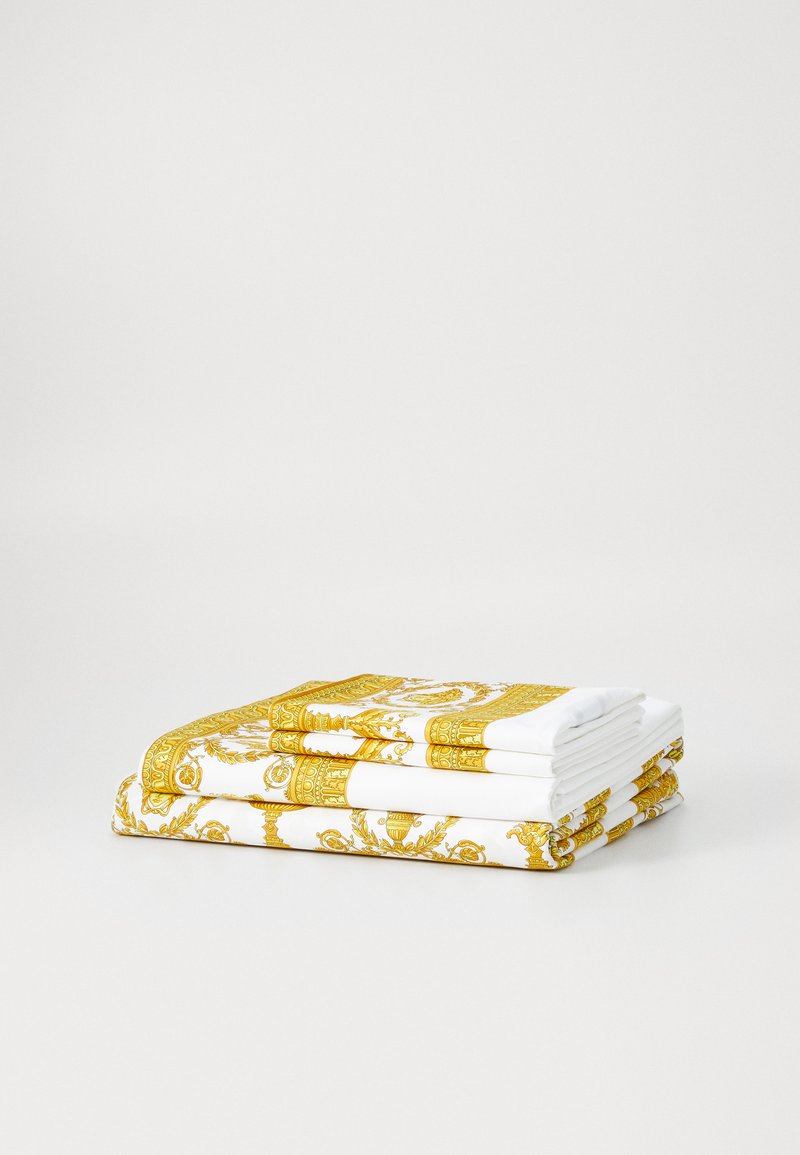 Fehér törölközőkészlet arany barokk mintával, részletes mintázattal az éleken. Puha anyag, szépen hajtogatott, több rétegben.