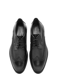 Ein Paar schwarze Leder-Brogueschuhe mit Wingtips und Schnürsenkeln, von oben auf einem weißen Hintergrund gezeigt.