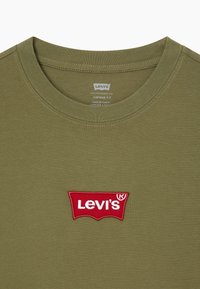 Olive green cotton t-shirt with a red embroidered Levi's logo. Features a round neckline and vintage fit. Smooth texture, minimal stitching.