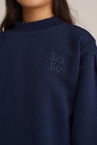 Tumši zilo treniņjakas, kas izgatavots no mīksta auduma, ar ribinātu apkakli un izšūtu "Dance" logotipu uz krūtīm.