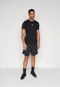 Black short-sleeve t-shirt with red-accented cuffs and collar. Worn with black shorts and black sneakers. Simple, athletic design.