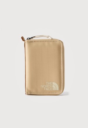 Compact beige portemonnee met ritssluiting en stoffen handvat, met het logo van "The North Face" aan de voorkant, rechtopstaand op een witte achtergrond.