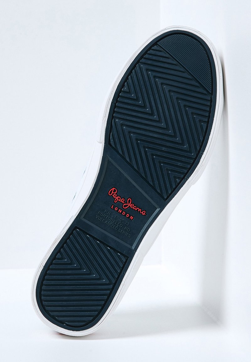 Semelle de sneaker blanche avec caoutchouc noir texturé ; présente des motifs en zigzag et le logo rouge "Pepe Jeans London" au milieu.