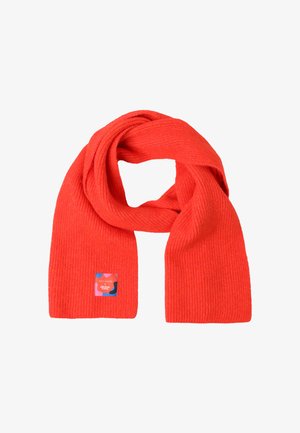 Écharpe rouge côtelée en matériau doux, comportant une étiquette carrée avec un design coloré et du texte à une extrémité.