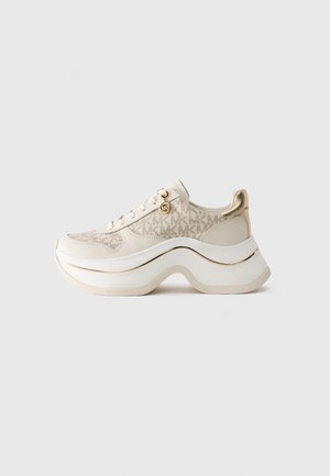 Sneaker platform beige e oro con motivo "MK", chiusura con lacci, charm dorato e suola spessa ondulata su sfondo semplice.