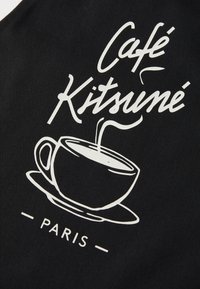 Svart stoff med hvit grafisk design av en kaffekopp og damp, med ordene "Café Kitsuné" og "PARIS" under.