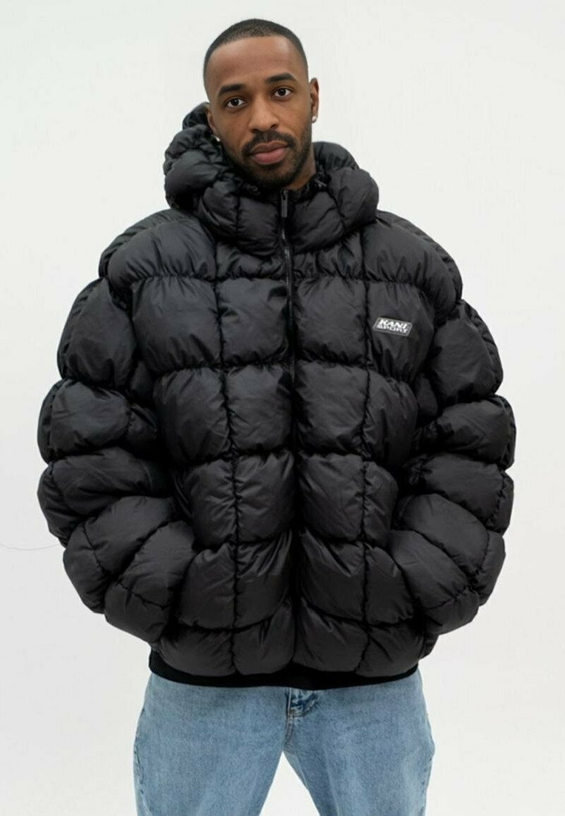 Doudoune noire avec un design matelassé, dotée d'un col montant et d'une fermeture éclair. Le tissu a l'air brillant et rembourré pour la chaleur.