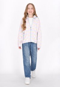 Giacca leggera con zip in colori pastello, caratterizzata da un motivo floreale circolare. Realizzata in tessuto morbido, presenta due tasche laterali ed è abbinata a jeans di jeans.
