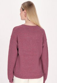 Túlméretezett pulóver egy puha, bordó anyagból, texturált felülettel. Kerek nyakkivágással és bordás mandzsetta részletekkel rendelkezik.