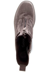 Brązowy zamszowy botek za kostkę z przednim zamkiem, zaokrąglonym noskiem i wyściełanym wzorem przy kostce. Logo widoczne na wewnętrznej podeszwie. Biała podeszwa.
