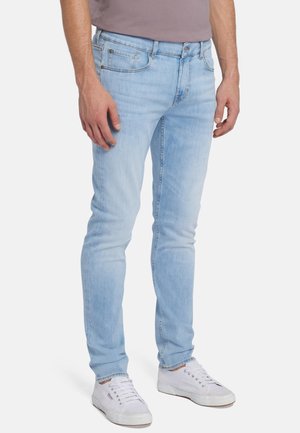 Lichtblauwe skinny jeans van denim, met een klassieke vijf-pocketontwerp en subtiele vervaging. Gekoeld met een grijs shirt en witte sneakers.