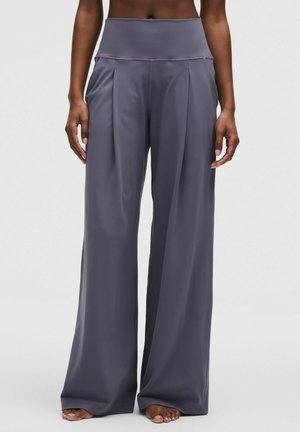 Široké kalhoty s vysokým pasem z měkké, pružné šedé látky s záhyby vpředu. Hladká textura bez viditelných kovových částí nebo vzorů.