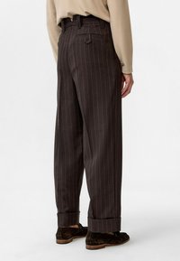 Bruine broek met streepjes in een relaxed fit, met een opgerolde zoom, achterzak en een riemlus bij de taille. Gladde stofstructuur.