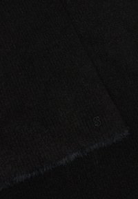 Écharpe noire en tissu texturé, présentant un logo discret sur un bord et des franges aux extrémités pour plus de détails.