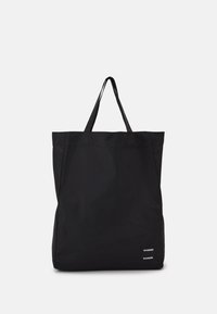 Borsa tote nera realizzata in tessuto resistente, con due manici robusti e un piccolo etichetta del marchio nell'angolo in basso a destra.