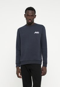 Navyblauwe sweatshirt gemaakt van zachte stof, met een wit geborduurd "Aspen" logo op de linkerkant van de borst en ribgebreide manchetten en onderkant.