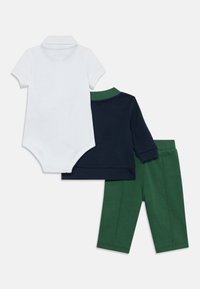 Tre-dels babyoutfit bestående av en vit polo-body, en marinblå långärmad tröja och gröna byxor, alla i mjuk bomullstyg.