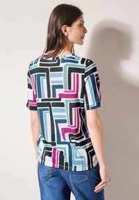 T-shirt en coton à manches courtes présentant un motif géométrique dans des nuances de bleu, rose et noir, avec un col rond et une coupe décontractée.