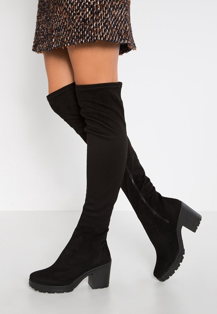 Bottes noires au-dessus du genou en daim doux, dotées d'un talon épais, d'une fermeture éclair à l'arrière et d'un tissu texturé.