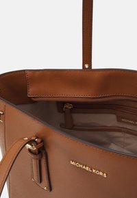 Bruine leren tote met goudkleurige hardware, beschikt over een ruime binnenkant, een ritsvak en een stevige handgreep. Gladde textuur en onopgesmukt ontwerp.