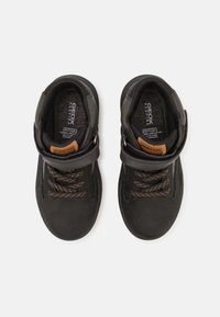 Černé vysoké tenisky s vrchní částí z textilie a semiše. Mají hnědé kožené detaily, texturované černé tkaničky a prodyšný interiér.