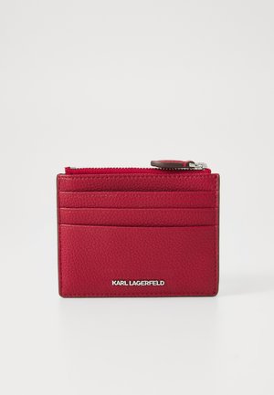 Red textured leather cardholder featuring multiple card slots and a zippered compartment. Silver logo detail at the bottom front.