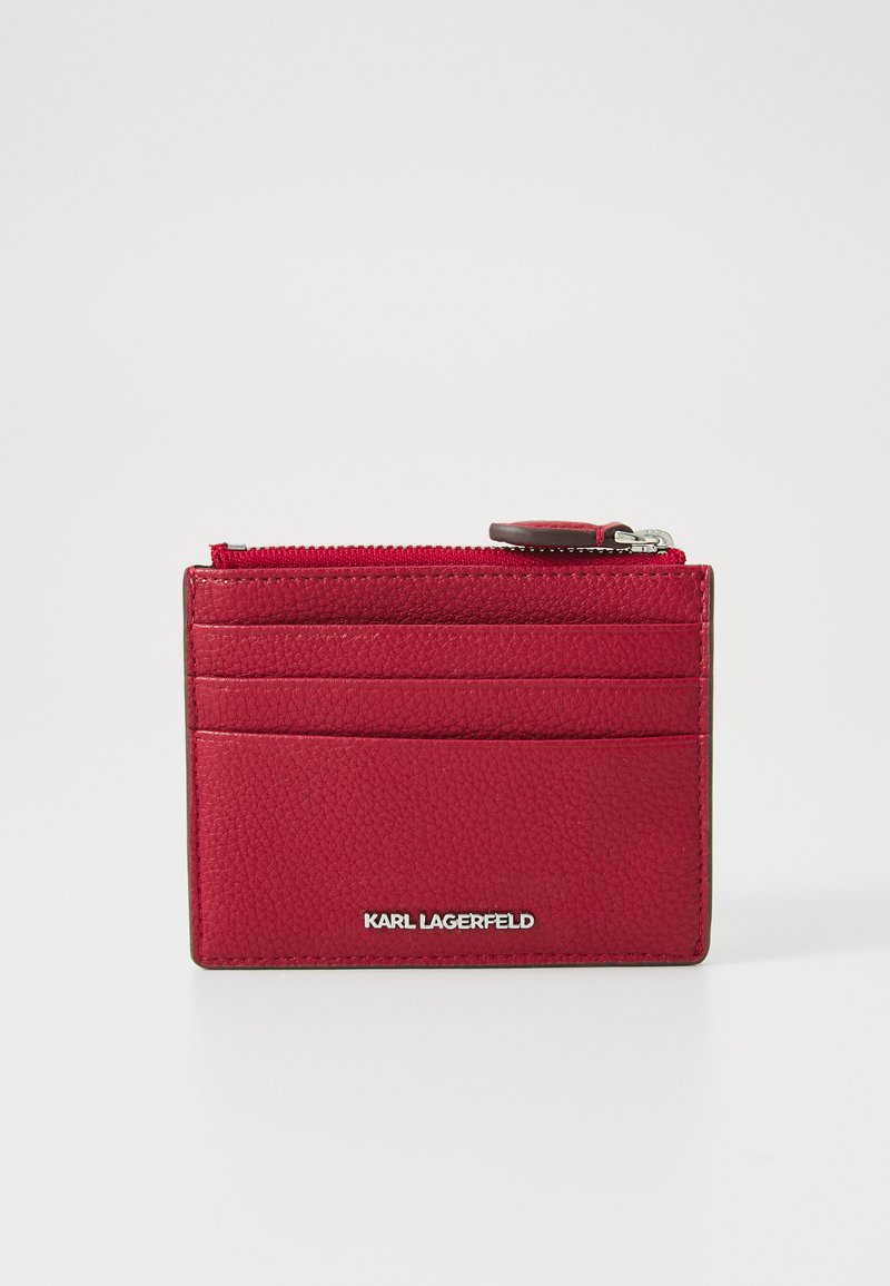 Carteira em couro vermelho texturizado com vários slots para cartões e um compartimento com fecho. Detalhe em logotipo prateado na parte inferior frontal.