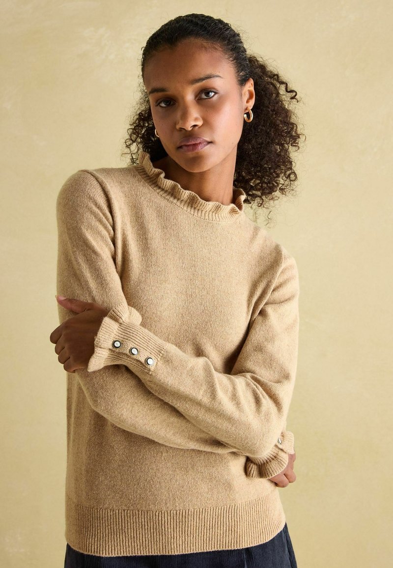 Beiger Pullover aus weichem Material. Mit geripptem Halsausschnitt und Bündchen sowie Knopfakzenten. Schlichtes Design mit lockerer Passform.