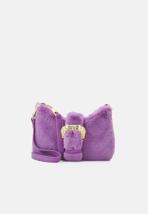 Bolso de hombro de felpa morado con hebilla dorada de Versace Jeans Couture y correa de cuero ajustable sobre un fondo blanco.