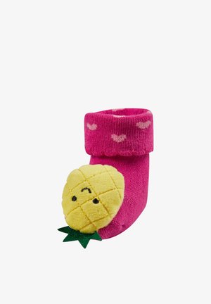 Bright pink baby sock with light pink hearts and a plush yellow smiling pineapple attached near the toe.