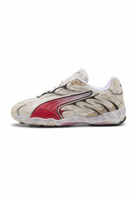 Beige atletiske sko med røde accenter og sorte detaljer, med et bølget tekstureret design, hvid polstret krave og gummisål.