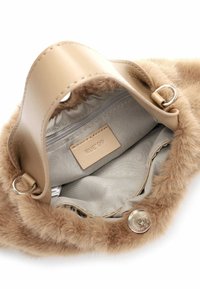Borsa in pelliccia sintetica beige con una texture morbida, hardware in argento, tasca interna con zip e un'etichetta rettangolare contrassegnata "RUE 09."