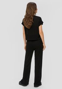 Zwart gestreepte tweedelige outfit met een relaxte, cropped top met opgerolde mouwen en wijde broekspijpen met zijsplitten. Glad textuur.