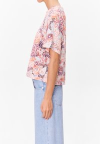 Kraťasový květinový top v pastelových barvách, s abstraktními vzory, volným střihem a kulatým výstřihem. Skvěle se hodí k světle modrým džínům.