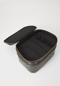 Svart glidelåsbag med geometrisk mønster, gullfarget metallisk detaljer og myk svart innside med flere elastiske rom for organisering.