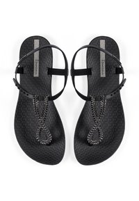 Black flat sandals made of textured rubber. Features a beaded chain detail and adjustable straps for a secure fit.
