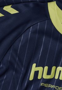 Marinblå sporttröja med vertikala ränder, en limegrön krage och "hummel"-logotyp i fet stil på framsidan. Mjuk, andningsbar tyg.