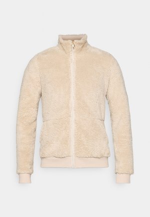 Helle beige Fleecejacke mit steigendem Kragen, durchgehendem Reißverschluss, elastischen Bündchen und einer weichen, strukturierten Oberfläche.