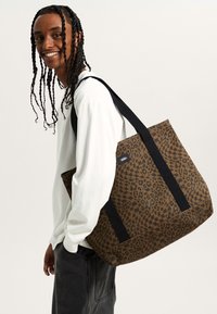 Shopper met luipaardprint in bruin met zwarte accenten. Voorzien van twee stevige schouderbanden en een rechthoekige vorm, gemaakt van duurzaam stof.