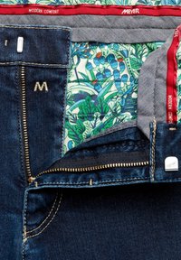 Donkerblauwe spijkerbroeken die gedeeltelijk zijn open geritst om de bloemenvoering te laten zien, grijze tailleband met rode rand en "Modern Comfort" en "Meyer" merknamen.