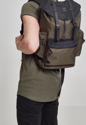 Sac à dos vert olive avec un rabat supérieur, accents noirs, bretelles ajustables et poches latérales. Fabriqué en matériau texturé et durable.