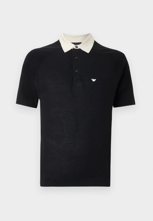 Fekete rövid ujjú galléros póló fehér gallérral, három fekete gombbal és kis fehér sas logóval a bal mellrészen.